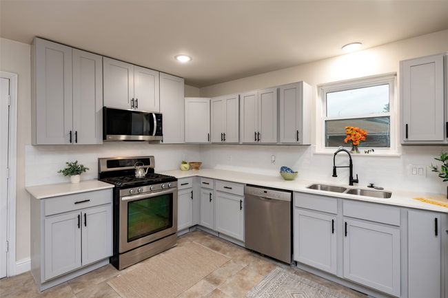 Kitchen featuring appliances with stainless steel finishes, a sink, light countertops, tasteful backsplash, and gray cabinets | Image 9