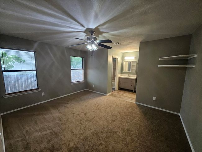 Unfurnished bedroom with a textured ceiling, visible vents, carpet flooring, connected bathroom, and baseboards | Image 20