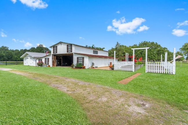 The front white barn is extremely versatile! Notice the word versatile being used with this property often! Great for storage, horses, farm equipment, etc. Notice the large garden with planters as well! No need to go to the grocery store for vegetables anymore! Don't forget to look inside the storage garage to the left of the barn! | Image 35