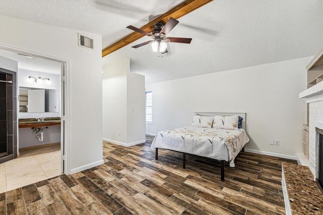 This secondary bedroom has high ceilings, a full ensuite bathroom with ADA entry and sink, private back entry, wood beamed ceiling and a sizeable closet | Image 27