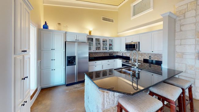 Kitchen featuring stainless steel appliances, a breakfast bar, visible vents, dark countertops, and glass insert cabinets | Image 9