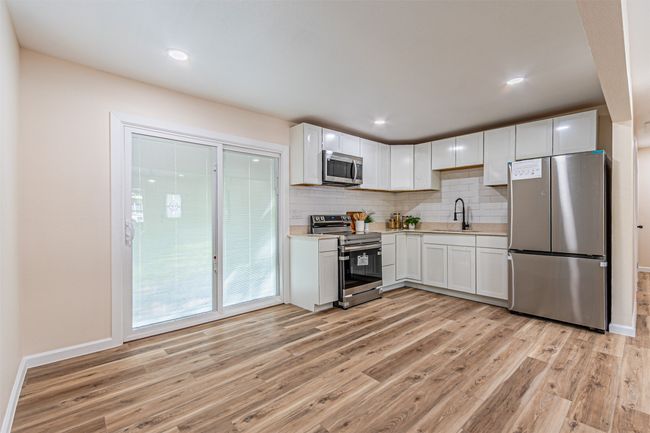 Kitchen with appliances with stainless steel finishes, light wood-style flooring, a sink, and light countertops | Image 8