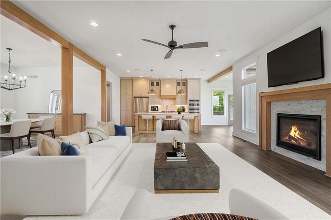 Living room featuring light wood-type flooring, a glass covered fireplace, a ceiling fan, recessed lighting, and a chandelier | Image 20