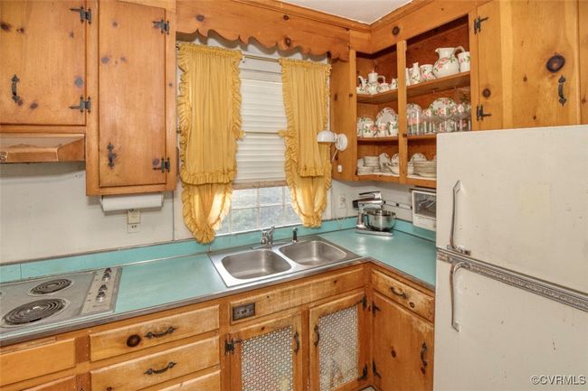 Kitchen with a sink, light countertops, freestanding refrigerator, stainless steel electric stovetop, and under cabinet range hood | Image 23