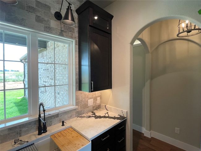 Kitchen featuring dark cabinets, light countertops, backsplash, dark wood-style flooring, and arched walkways | Image 30