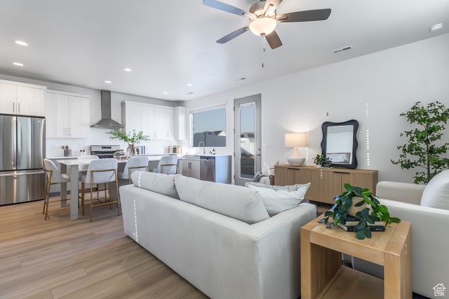 Living area featuring light wood-style flooring, ceiling fan, and recessed lighting | Image 6