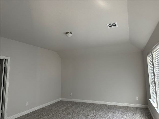 Unfurnished room with lofted ceiling, dark colored carpet, and plenty of natural light | Image 10