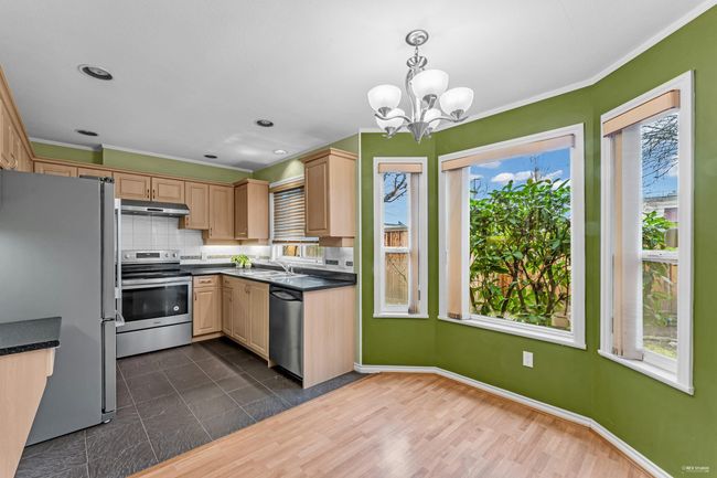 Kitchen with dark countertops, backsplash, appliances with stainless steel finishes, and under cabinet range hood | Image 11