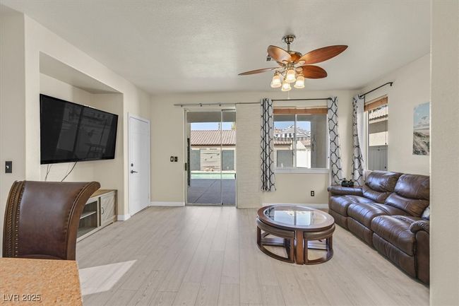 Living area featuring a textured ceiling, baseboards, a ceiling fan, and wood finished floors | Image 10