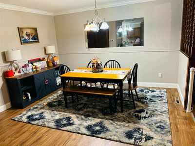 Dining area with ornamental molding, a notable chandelier, and hardwood / wood-style floors | Image 2