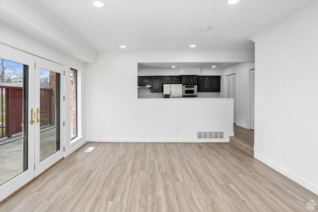 Unfurnished living room with light wood-style flooring, crown molding, baseboards, and visible vents | Image 13