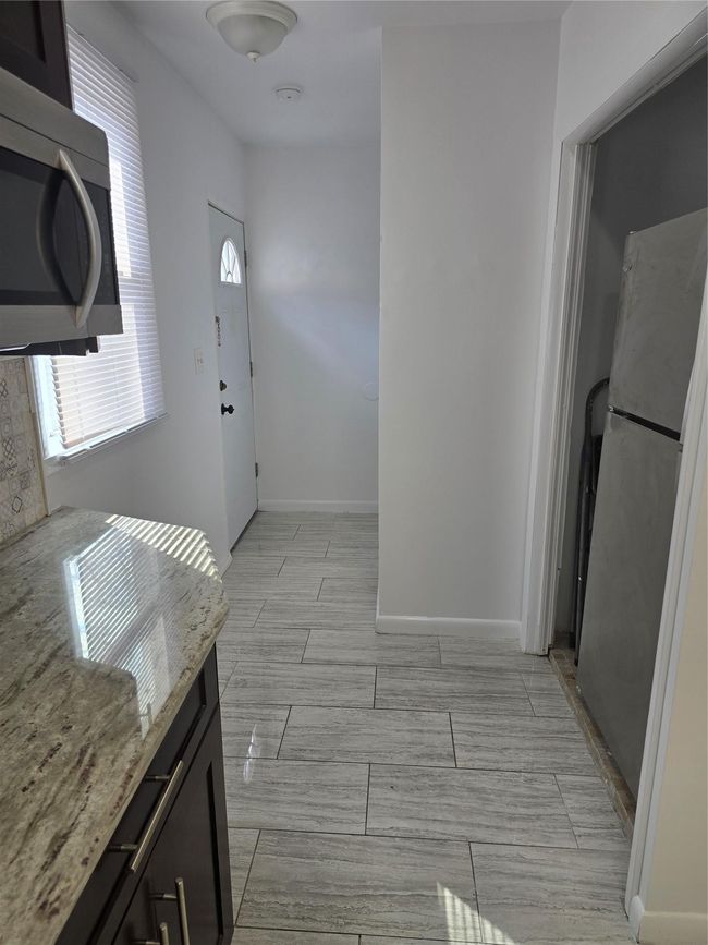 Kitchen with baseboards, fridge, wood tiled floor, and light stone countertops | Image 7