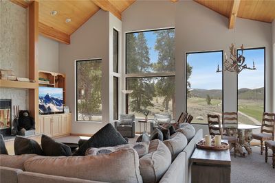 Carpeted living room with wooden ceiling, a wealth of natural light, a fireplace, and high vaulted ceiling | Image 2