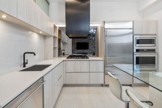 Kitchen featuring light countertops, a sink, built in appliances, modern cabinets, and extractor fan | Image 10