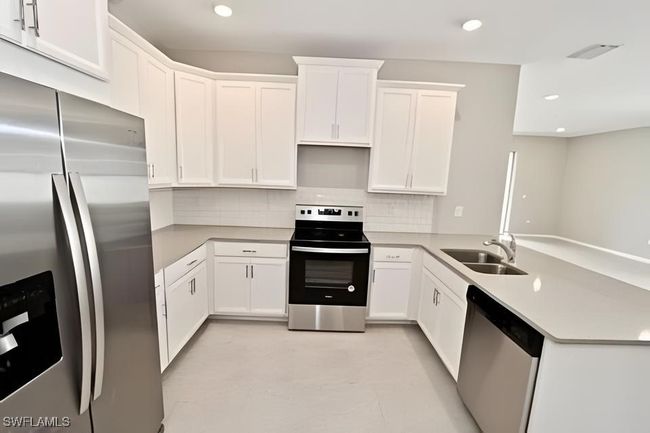 Kitchen featuring appliances with stainless steel finishes, a sink, backsplash, a peninsula, and recessed lighting | Image 13