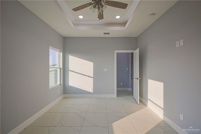 Empty room with ceiling fan and a raised ceiling | Image 14