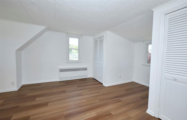 Bedroom with radiator, wood finished floors, baseboards, and lofted ceiling | Image 17