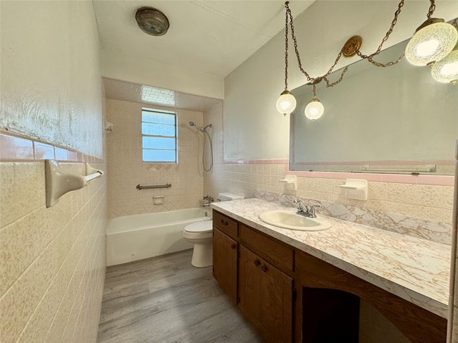 Full bathroom featuring wood-type flooring, tile walls, tiled shower / bath combo, vanity, and toilet | Image 21