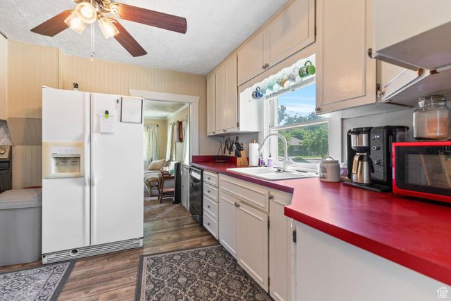 Kitchen featuring white fridge with ice dispenser, a sink, black dishwasher, dark wood-style floors, and ceiling fan | Image 8