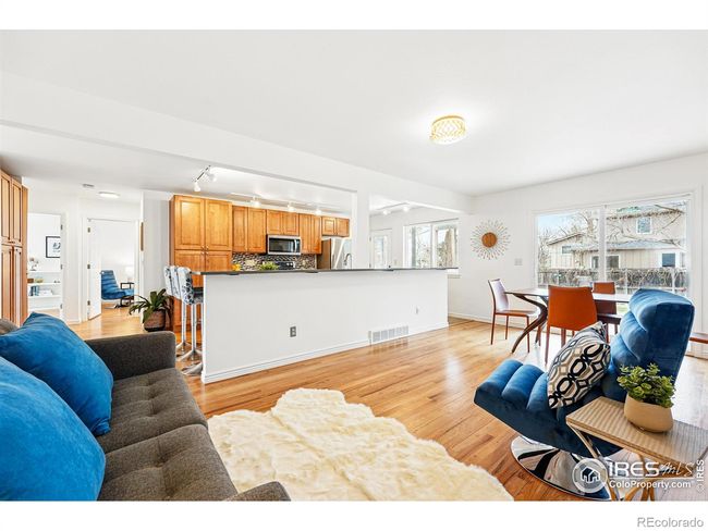 gleaming wood floors in the main level sitting area, dining room, bedroom and hallway. modern tile flooring and stainless steel appliances with generous cabinet space | Image 9