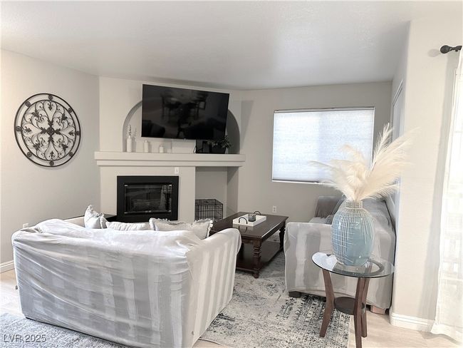 Living room featuring baseboards, wood finished floors, and a glass covered fireplace | Image 5