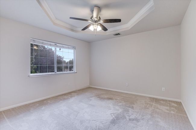 Carpeted spare room featuring a tray ceiling, ornamental molding, a ceiling fan, and baseboards | Image 16