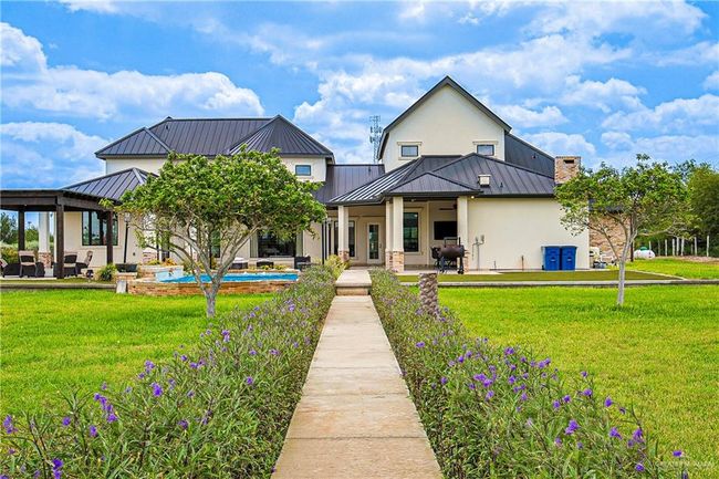 Back of house with stucco siding, a standing seam roof, a patio, and a lawn | Image 36