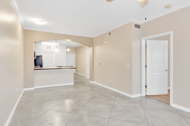 Living/dining room with crown molding, arched walkways, and new ceiling fan. All new paint. | Image 7