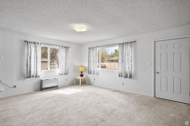 Empty room with carpet floors, heating unit, and plenty of natural light | Image 16