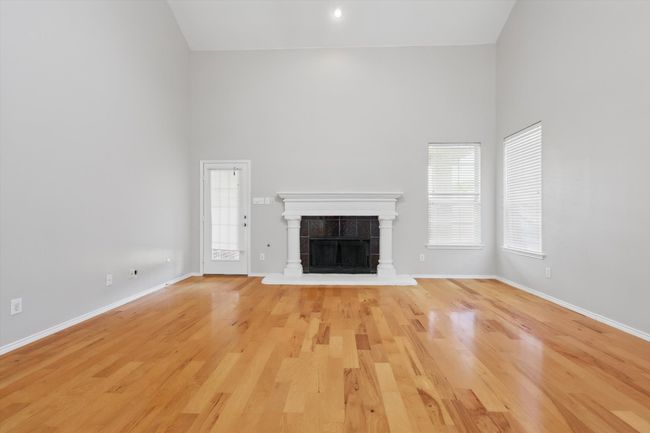 Unfurnished living room with high vaulted ceiling, light wood-style floors, a tile fireplace, and baseboards | Image 9