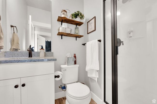 Bathroom with toilet, a stall shower, vanity, wood finished floors, and baseboards | Image 15