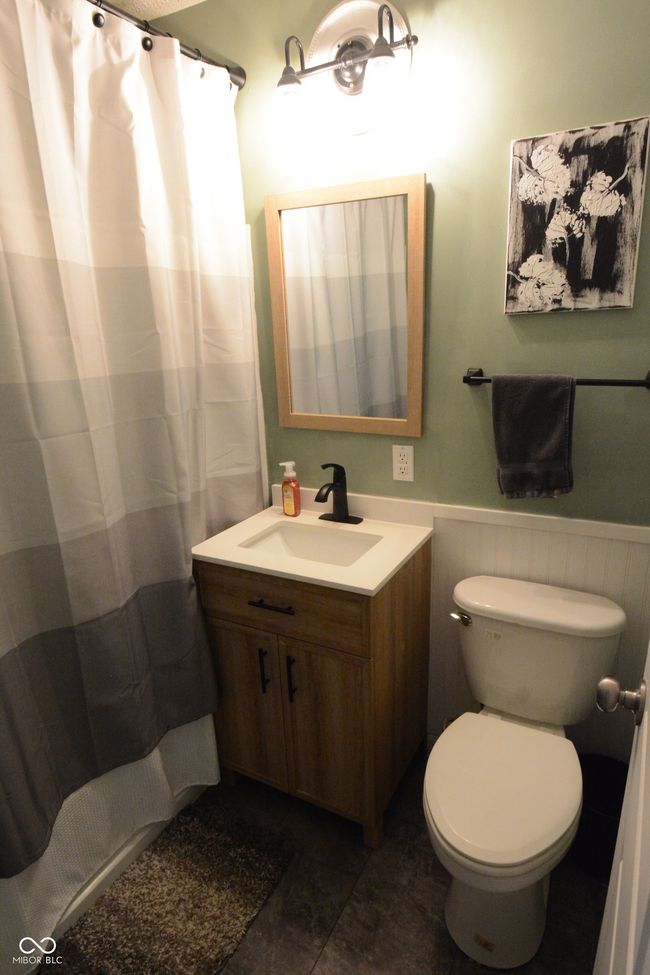 full bathroom featuring curtained shower, a wainscoted wall, vanity, and toilet | Image 16