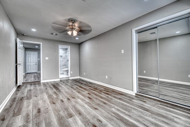 Unfurnished living room with ceiling fan, wood finished floors, a textured ceiling, and a textured wall | Image 7