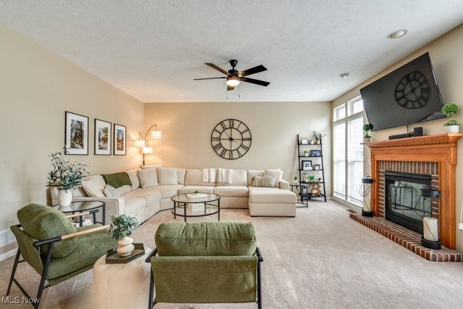 Living area featuring carpet floors, a ceiling fan, a brick fireplace, and a textured ceiling | Image 14