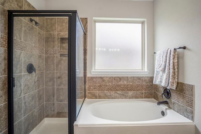 Take a closer look at the beautifully detailed tile shower and soaking tub. A large window above the tub fills the space with natural light, while intricate tile insets and a recessed soap niche in the shower add subtle touches of elegance and practicality. | Image 21