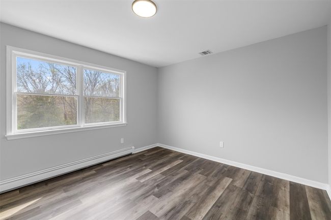 Spare room featuring a baseboard radiator, a healthy amount of sunlight, visible vents, and dark wood-type flooring | Image 18