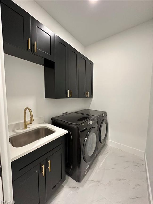 Washroom with cabinets, washer and dryer, and sink | Image 39
