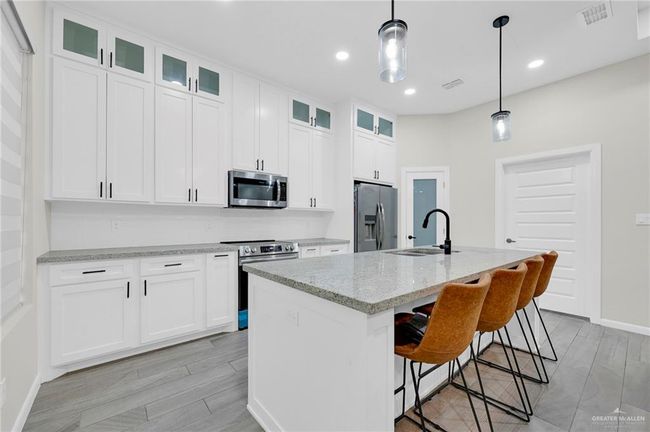 Kitchen with light wood-style tile flooring, a sink, appliances with stainless steel finishes, and visible vents | Image 12