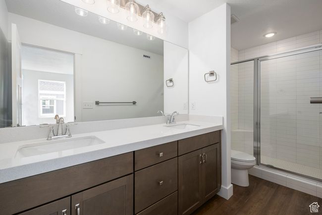 Bathroom with toilet, a stall shower, wood finished floors, and a sink | Image 14