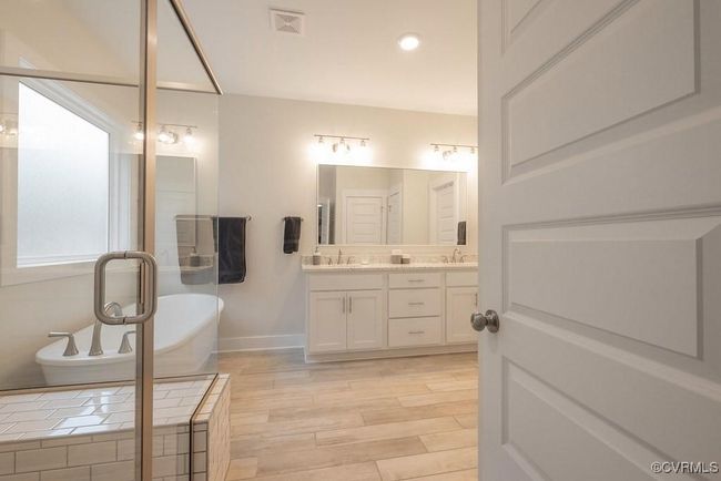 Bathroom featuring a freestanding bath, double vanity, and wood finished floors | Image 17