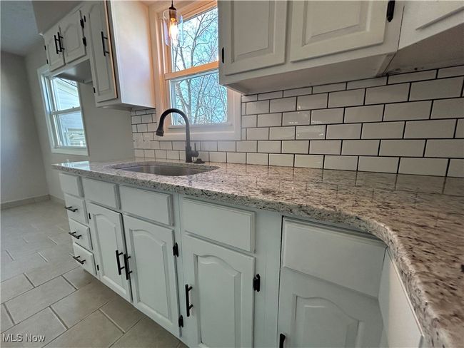 Kitchen featuring white cabinetry, plenty of natural light, tasteful backsplash, and a sink | Image 7