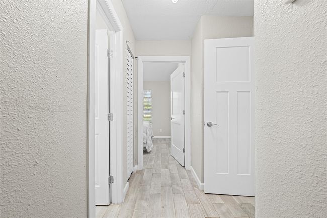 Hallway with light wood-style floors and a textured wall | Image 23