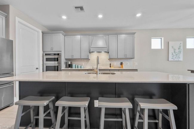 Kitchen with visible vents, gray cabinets, a sink, tasteful backsplash, and stainless steel double oven | Image 30