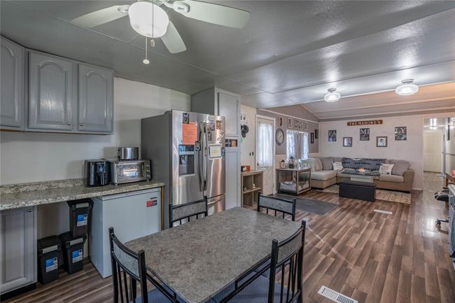 Kitchen featuring stainless steel fridge, a ceiling fan, dark wood-style flooring, open floor plan, and vaulted ceiling | Image 5