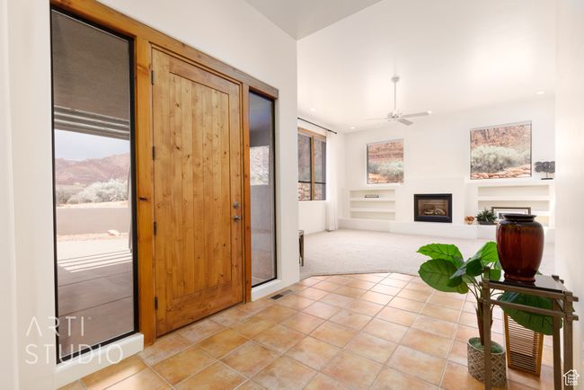 Entrance foyer featuring ceiling fan, light carpet, a fireplace, light tile patterned floors, and visible vents | Image 11