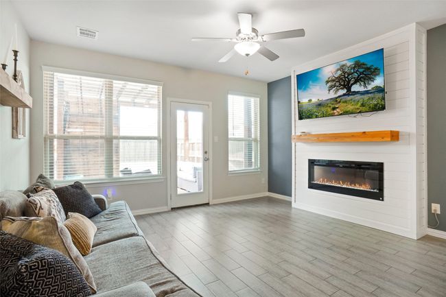 Living room featuring a glass covered fireplace, baseboards, a ceiling fan, and wood finished floors | Image 4