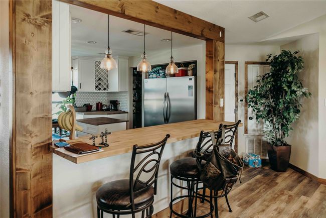 Kitchen featuring freestanding refrigerator, tasteful backsplash, butcher block countertops, wood finished floors, and a peninsula | Image 7