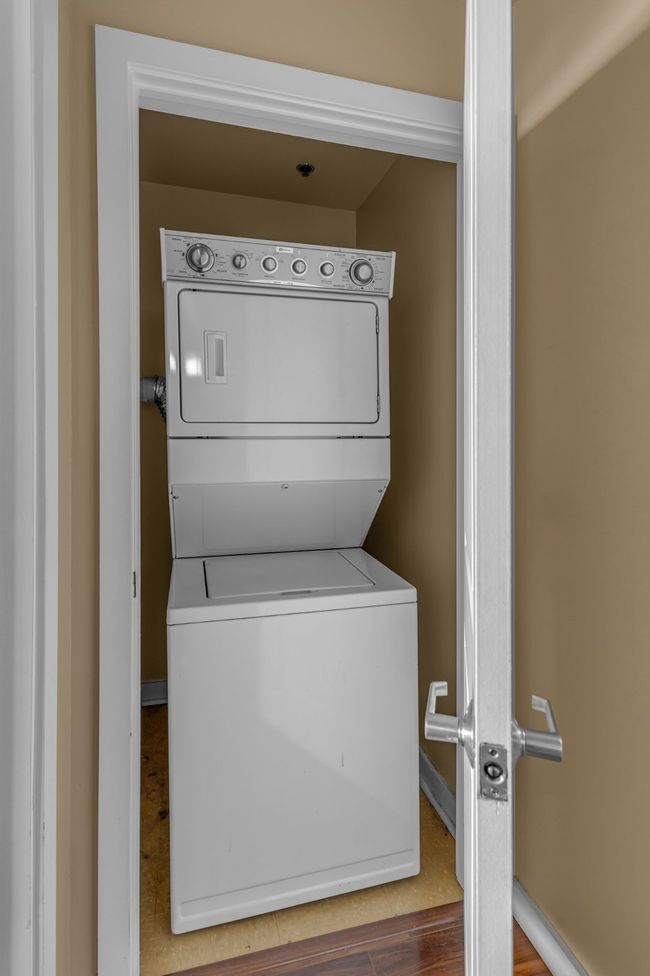 Washroom featuring wood finished floors, baseboards, stacked washer / dryer, and laundry area | Image 14