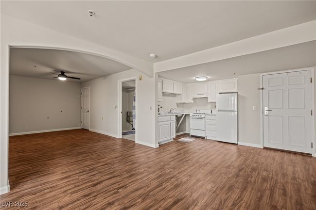 Unfurnished living room with baseboards, arched walkways, a ceiling fan, and dark wood-type flooring | Image 9