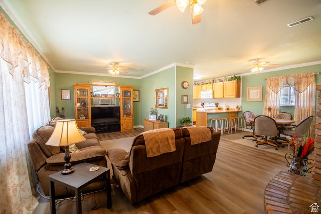 Living area with a ceiling fan, wood finished floors, and ornamental molding | Image 9